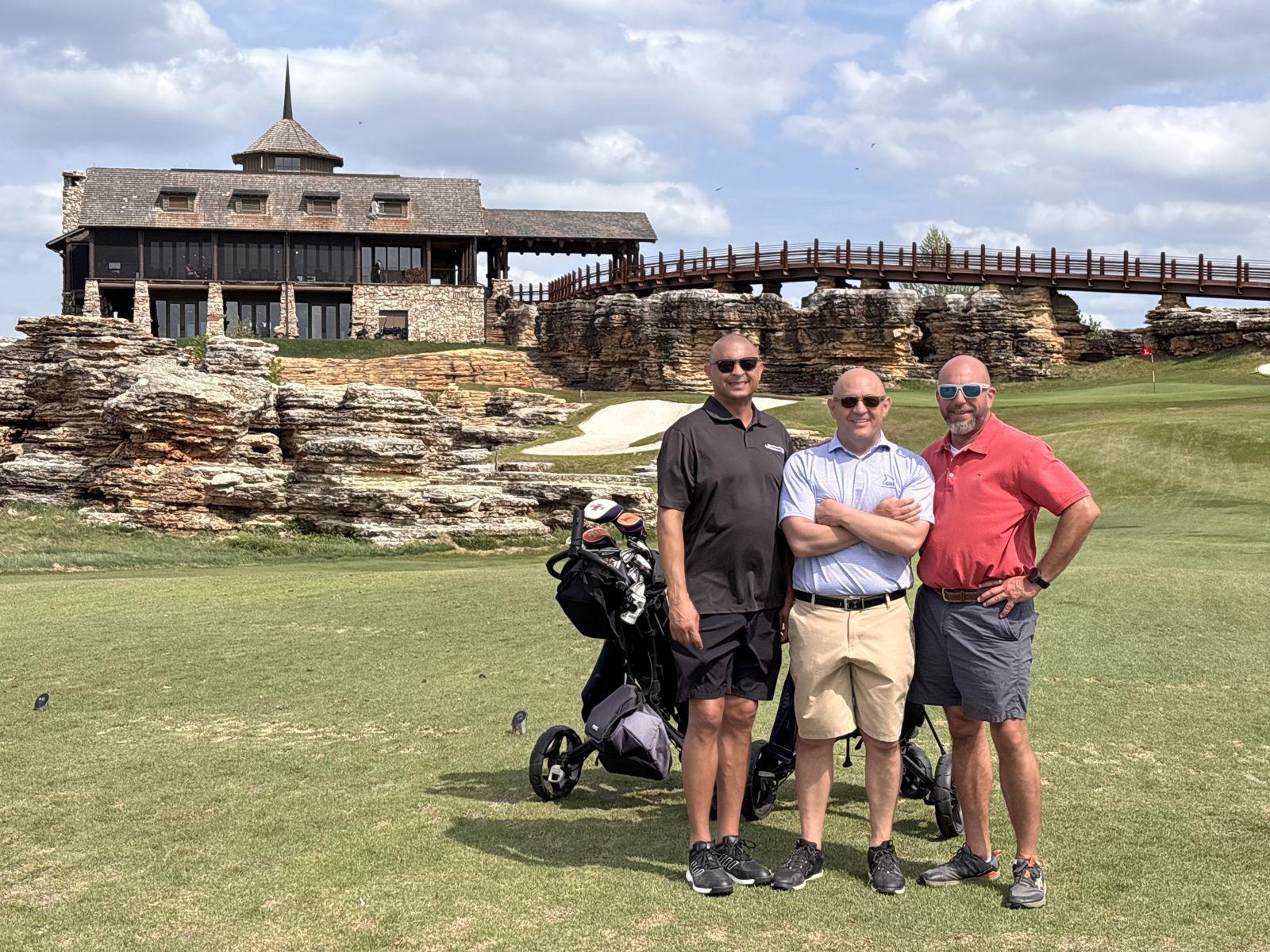 Golfers on the fairway at Top of the Rock, with the clubhouse and stone arch bridge behind them near Branson