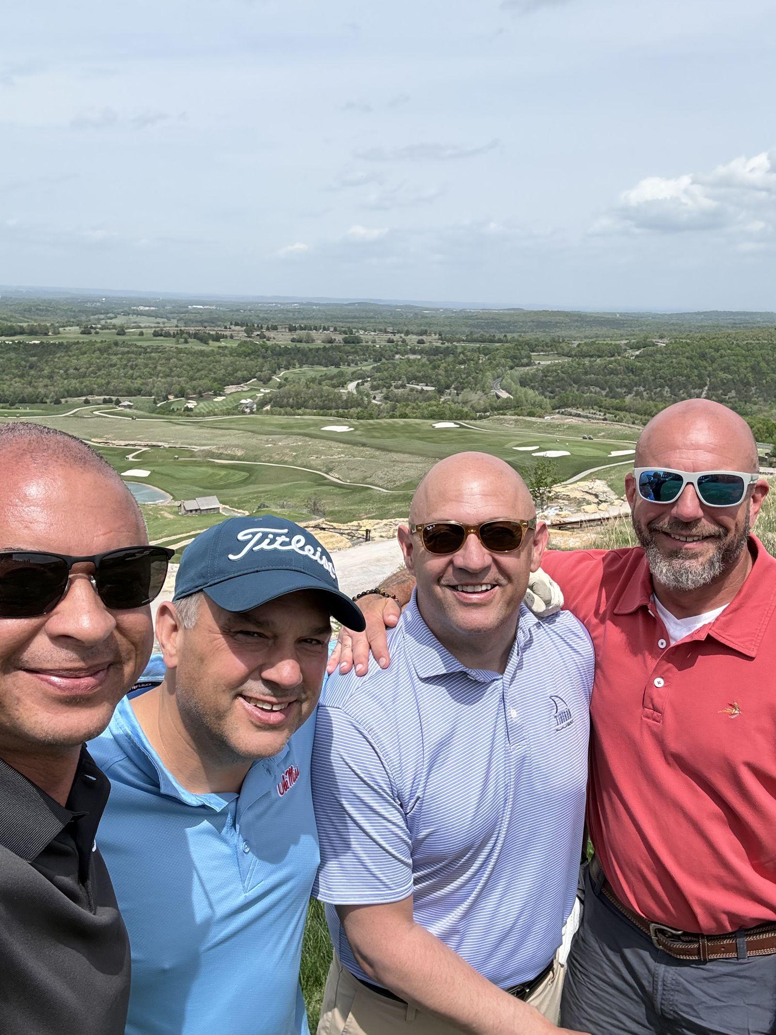 Golfers at the Top of the Rock clifftop overlook, the golf course and Ozark hills stretching out behind