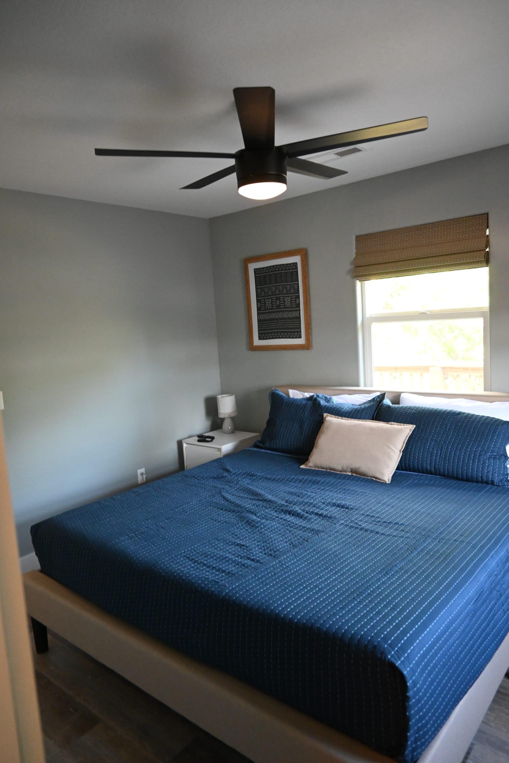 Bright primary bedroom with king bed and ceiling fan in Suite 2