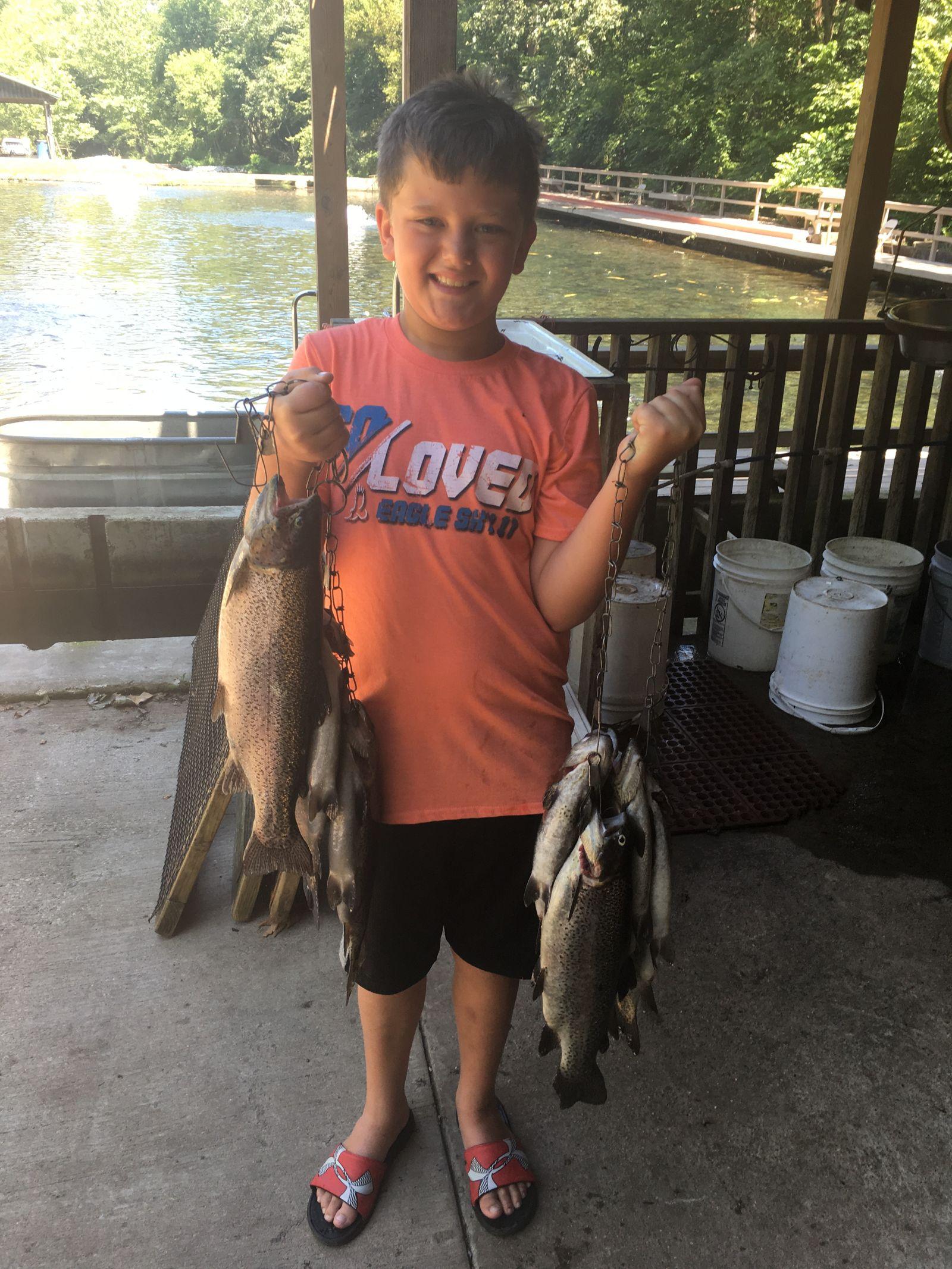 A child proudly holding a stringer of rainbow trout caught at the spring-fed ponds at Mountain Springs Trout Park