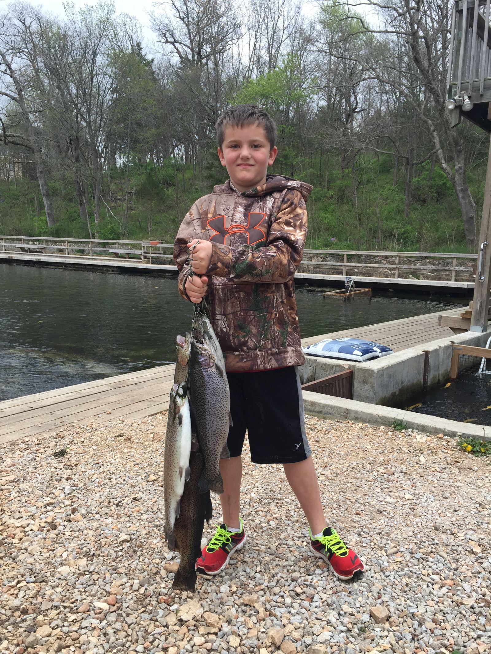 A young angler holding two freshly caught trout beside the spring-fed channel at Mountain Springs Trout Park
