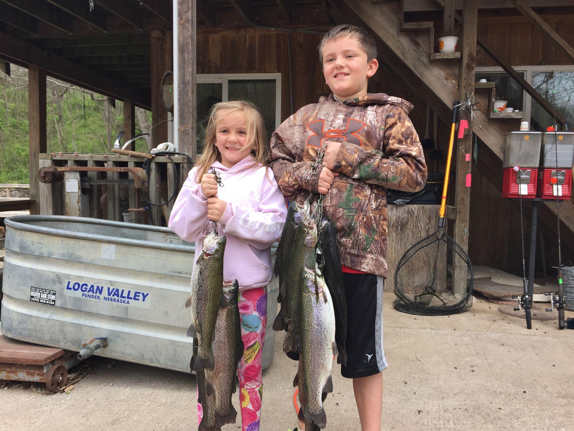 Two smiling children holding up stringers of rainbow trout under the pavilion at Mountain Springs Trout Park near Branson